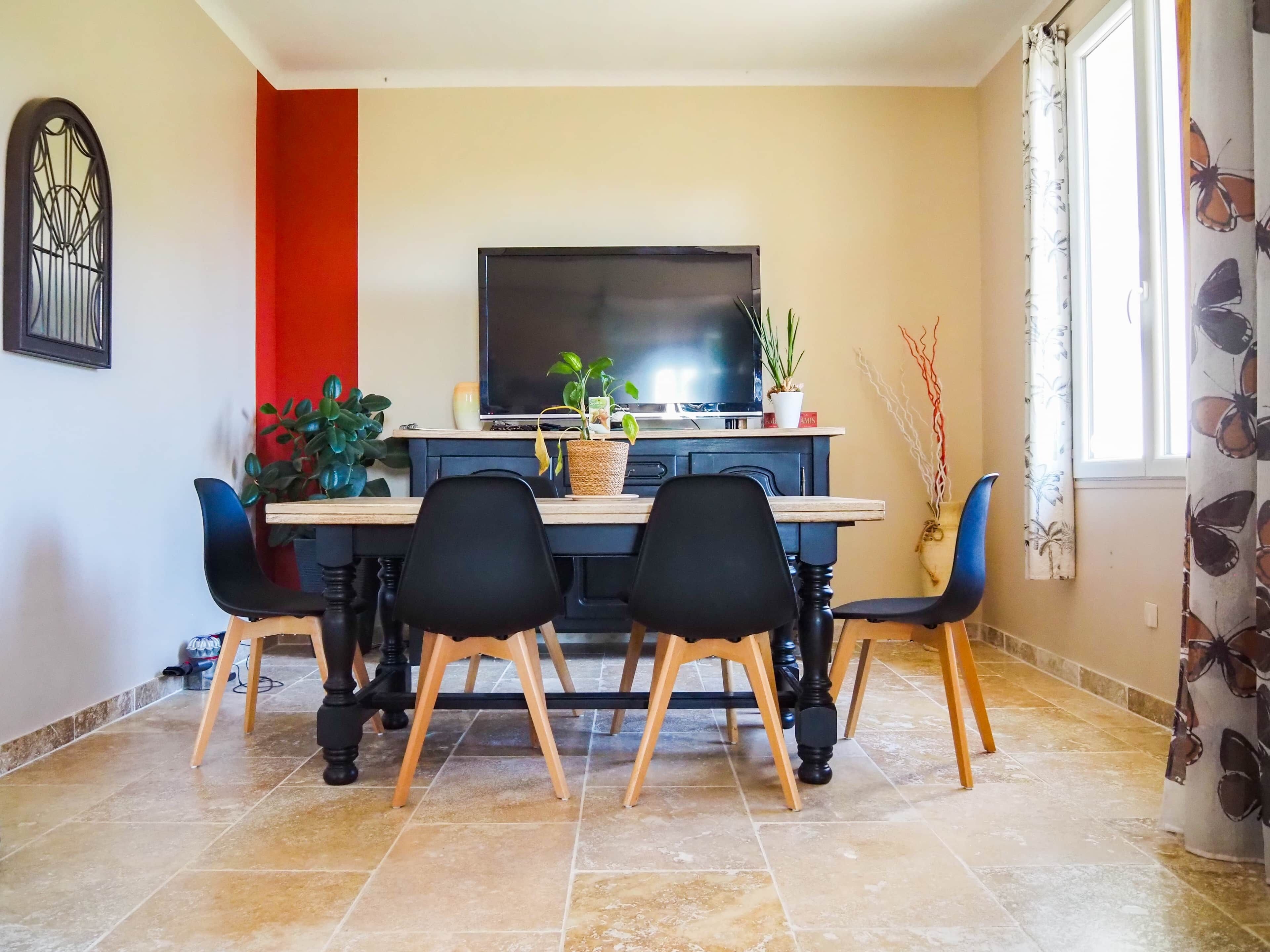 A dining area with a table, chairs, a TV, and potted plants.