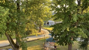 A parking area with a paved walkway, trees, and a building in the background. - Hotel Sächsischer Hof (Scheibenberg)