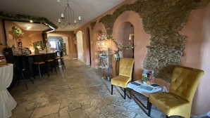 A hotel lobby with stone flooring, a bar area, and seating with yellow chairs. - Hotel Sächsischer Hof (Scheibenberg)
