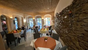A restaurant with tables set for dining, a stone wall, and arched windows. - Hotel Sächsischer Hof (Scheibenberg)