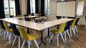 Un salón de conferencias con una gran mesa, sillas, botellas de agua y una pizarra.
