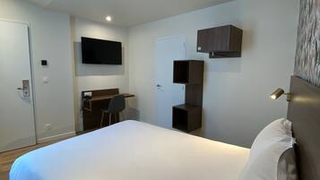 Una habitación de hotel moderna con una cama grande, un escritorio y un televisor de pantalla plana montado en la pared.