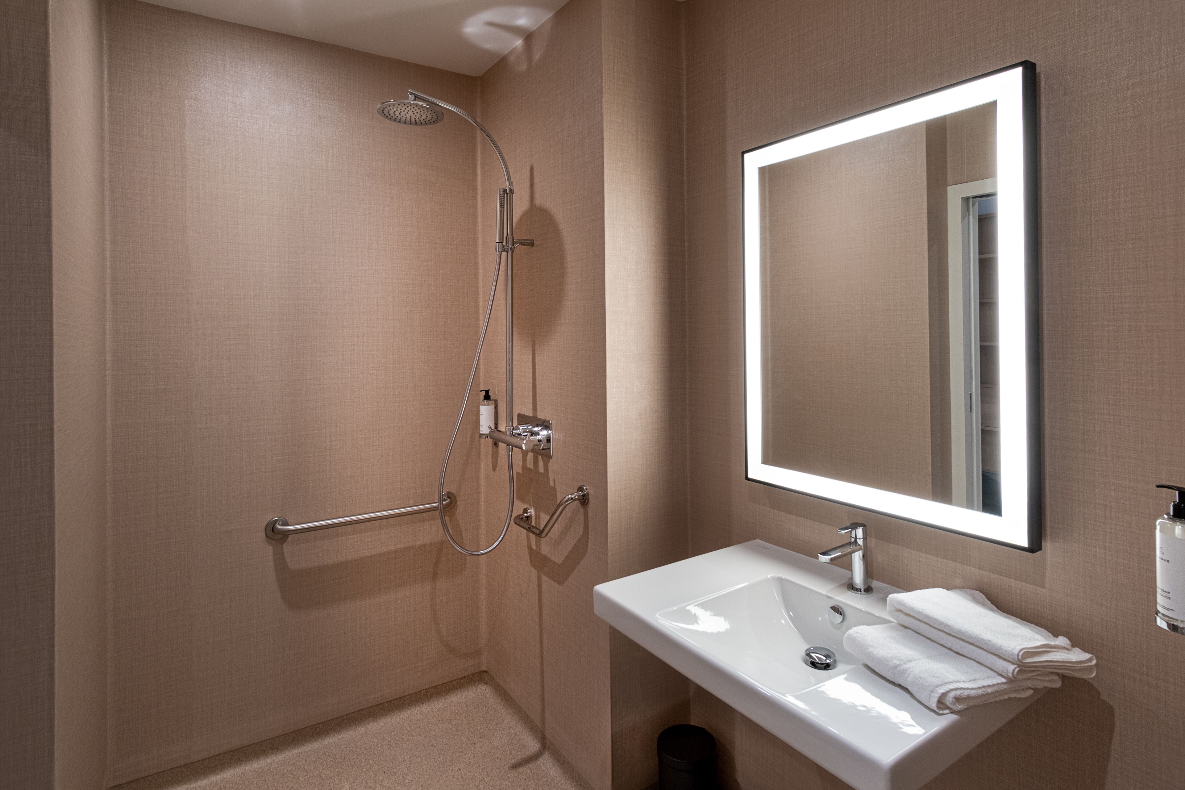 A modern bathroom with a shower, a sink, and a mirror.