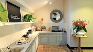 A modern kitchen with a skylight, a mirror, and a potted plant. - Villa Bloom 4 Bedroom (Seminyak)