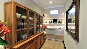A hallway with a wooden cabinet, a mirror, and a small plant. - Villa Bloom 4 Bedroom (Seminyak)
