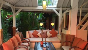 Un área de estar al aire libre acogedora, con mobiliario de madera y un suelo estampado.