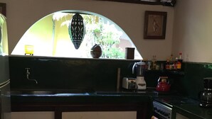 Una cocina con cubierta verde, estufa, fregadero y ventana con vista a la vegetación.
