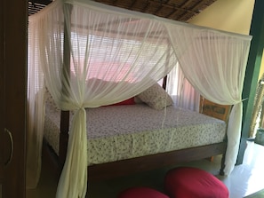 A bed with a canopy, a floral bedspread, and two pillows.