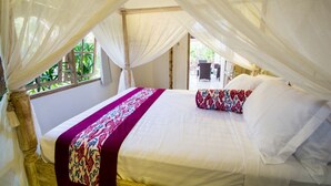 A bed with a canopy, a window, and a view of greenery outside. - Villa Mason 9 Bedroom (Seminyak)