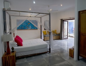 Un dormitorio con cama con dosel, ventilador de techo, ventana grande y vista al exterior.