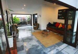 Una sala de estar moderna con sofá, sillas, una mesita de centro y un gran ventanal con vistas a un jardín.