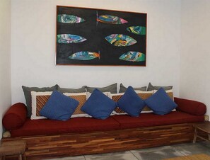 Un sofá rojo con cojines azules y un cuadro de un pez enmarcado encima.