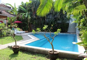 A swimming pool surrounded by lush greenery and potted plants. - Villa Mason 2 (Seminyak)