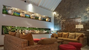 Uma sala de estar moderna com móveis de vime, uma parede de destaque em pedra e arte decorativa nas paredes.