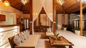 A spacious indoor area with a wooden ceiling, a dining table with chairs, and a sofa set. - Villa Kubu Joglo (Seminyak)