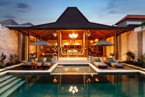 A modern resort with a swimming pool, a covered lounge area, and a dining space with a view of the pool. - Villa Kubu Joglo (Seminyak)