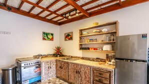 Uma cozinha com armários de madeira, forno de aço inoxidável, geladeira e piso ladrilhado.