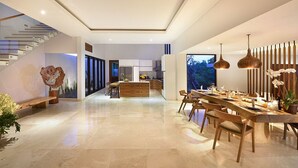 A modern kitchen with white cabinets, a central island, and pendant lighting. - Villa Serenita 3 Bedroom (Pecatu)