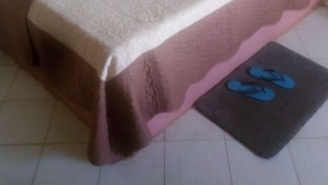 Un letto singolo con copriletto marrone e cuscino rosa.