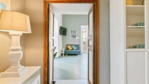 A hallway leading to a living room with a sofa and a lamp.