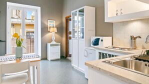 A modern kitchen with a built-in microwave, a sink, and a dining area with a table and chairs.