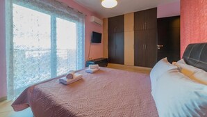 Een slaapkamer met een groot bed, een garderobe, een televisie en een raam met uitzicht.