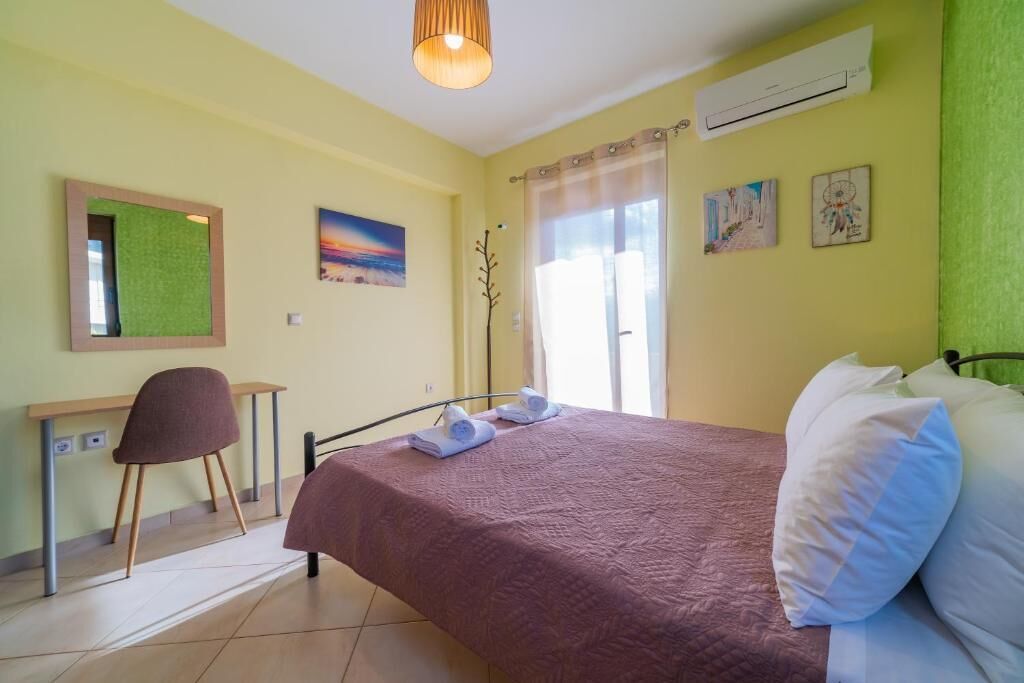 Une pièce comprenant un lit, un bureau et une chaise. On y trouve des serviettes sur le lit, une plante et des œuvres d’art accrochées aux murs.
