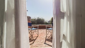 Eine Außenpatio-Terrasse mit zwei blauen Stühlen und einer dahinterliegenden Steinmauer.