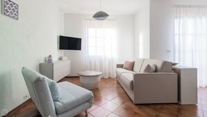 A modern living room with a sofa, a chair, a TV, and a small table. - Il Borgo apartments - A3 (Finale Ligure)