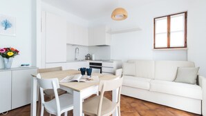 Un área moderna de estar y comedor con temática blanca, que incluye un sofá, una mesa de comedor y sillas.