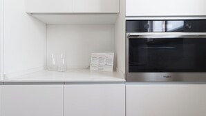 Uma cozinha moderna com forno Whirlpool de aço inoxidável, armários brancos e um guia de reciclagem sobre o balcão.