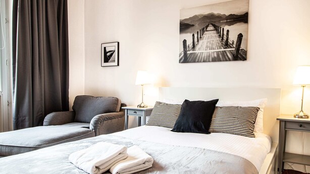 A hotel room with two beds, a sofa, a desk, and a lamp. - Powisle Superior Apartment (Warsaw)