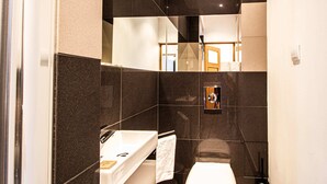 A modern bathroom with dark tiles, a white sink, and a mirror. - Powisle Superior Apartment (Warsaw)