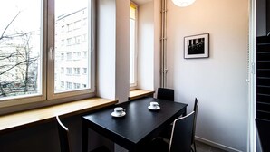 A modern room with a large window, a black table with two white cups, and a framed picture on the wall. - Powisle Superior Apartment (Warsaw)