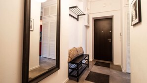 A hallway with a mirror, a bench, a door, and a wall-mounted shelf. - Powisle Superior Apartment (Warsaw)