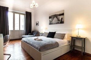 Ein modernes Schlafzimmer mit einem großen Bett, Nachttischen, einem Schreibtisch und einem Sessel.