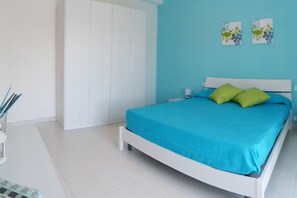 A bedroom with a bed, white wardrobe, and two wall art pieces.