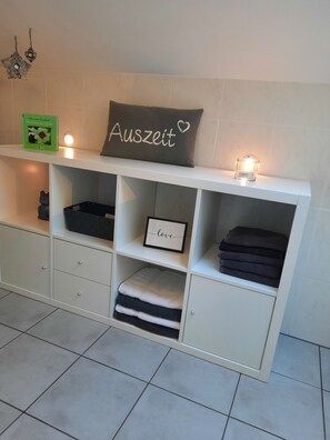Storage unit with ample space for personal items, featuring a shelf with a framed picture and a pillow with a heart symbol.