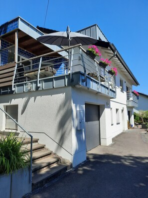 Enjoy a balcony view of the surrounding area from the upper level, with a covered outdoor seating area and a garage.