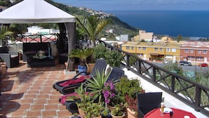 A terrace with outdoor seating, potted plants, and a view of the sea and buildings. - Holiday Home to the Street With big Kitchen (Icod de los Vinos)