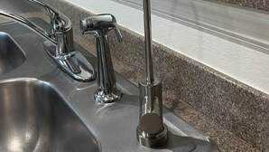 A kitchen with a stainless steel sink, a faucet, and a vase with white flowers on the counter. - All 5 star reviews, 6 bed, 5.5 bath, 4 king en-suites, Free pool, spa heat! (Kissimmee)