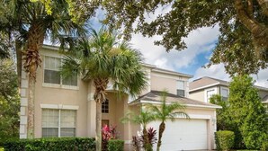 A two-story residential house with a front yard, palm trees, and a garage. - All 5 star reviews, 6 bed, 5.5 bath, 4 king en-suites, Free pool, spa heat! (Kissimmee)