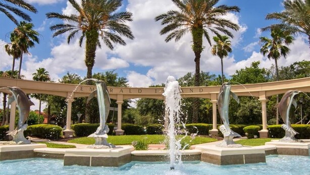 A fountain with dolphins, palm trees, and a sign reading "EMERALD ISLAND". - All 5 star reviews, 6 bed, 5.5 bath, 4 king en-suites, Free pool, spa heat! (Kissimmee)