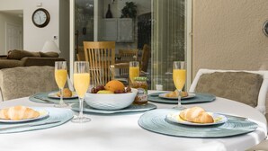 A breakfast table set with croissants, juice, and a bowl of fruit. - All 5 star reviews, 6 bed, 5.5 bath, 4 king en-suites, Free pool, spa heat! (Kissimmee)