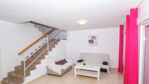 Una sala de estar con una escalera, dos sofás, una mesa de centro y un cuadro en la pared.