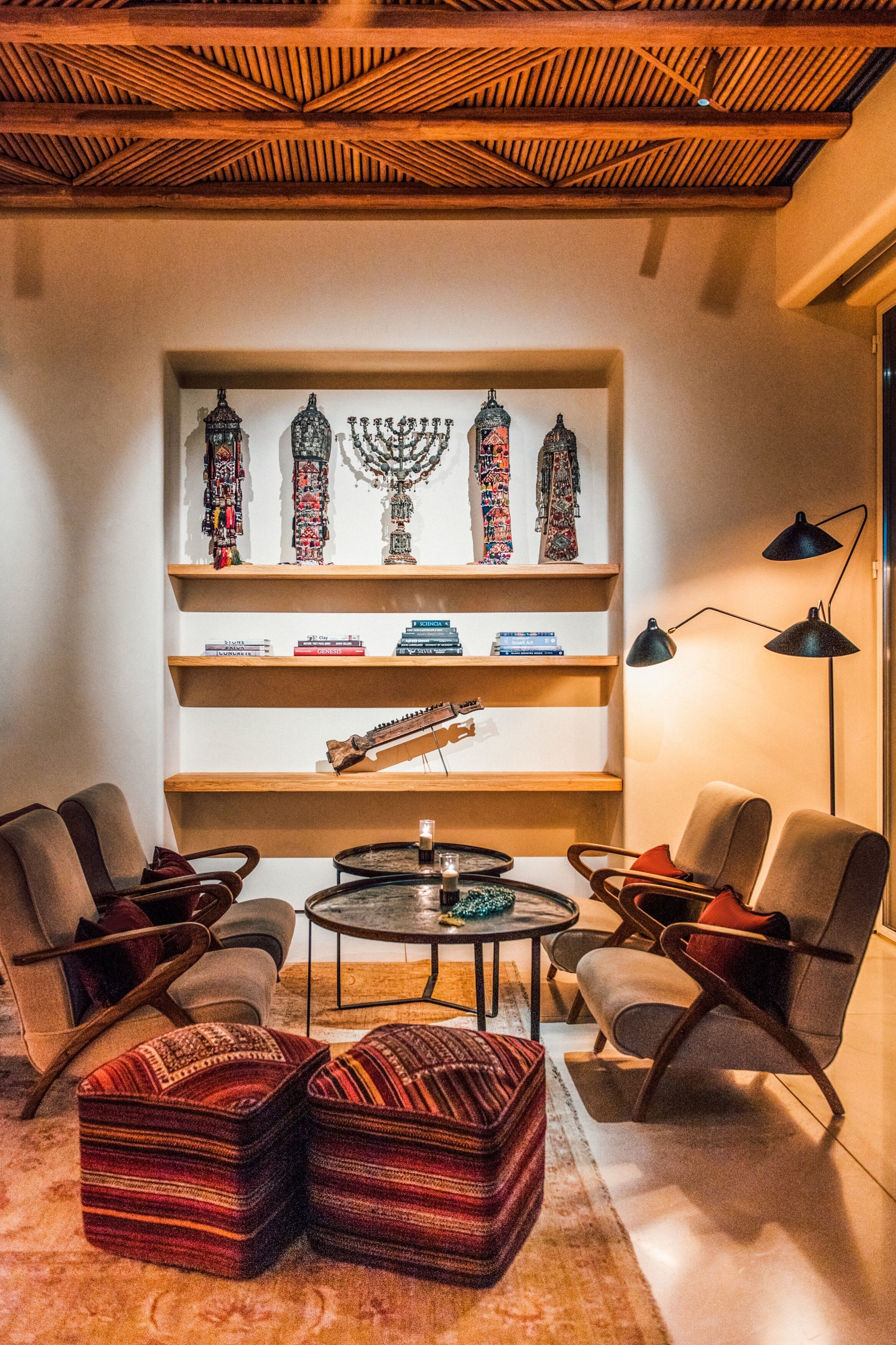 Ein modernes Wohnzimmer mit Holzboden, einem Bücherregal mit Dekorationsobjekten, einer Gitarre und bequemen Sitzgelegenheiten.