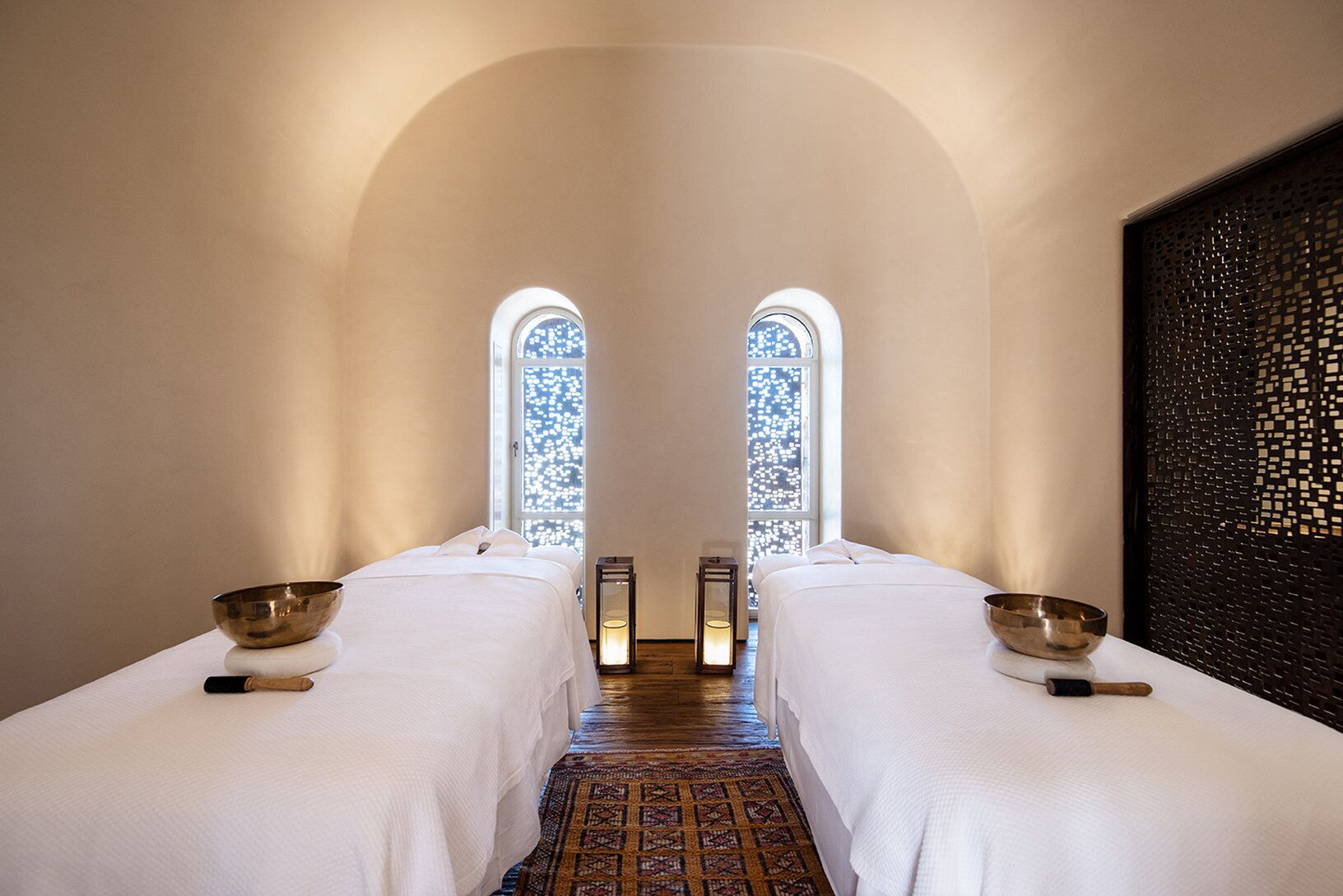 A room with two beds, a patterned carpet, and a decorative wall.