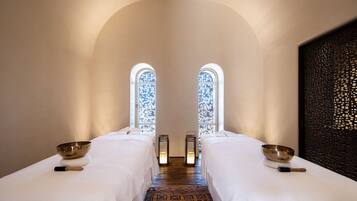 A room with two beds, a patterned carpet, and a decorative wall.