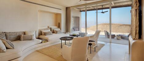 A modern living room with a curved sofa, a white armchair, and a coffee table.