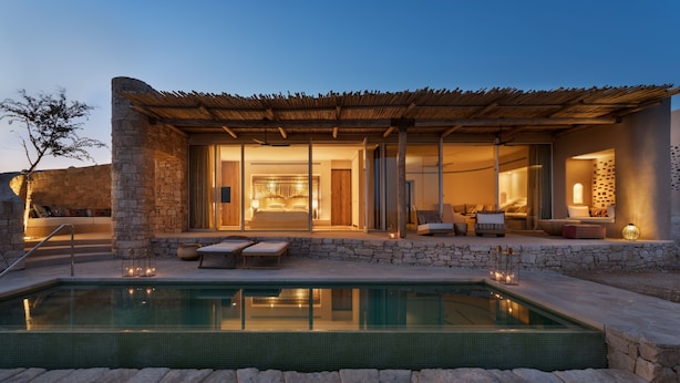A modern villa with a swimming pool, stone walls, and a cozy interior with a bedroom and living area.